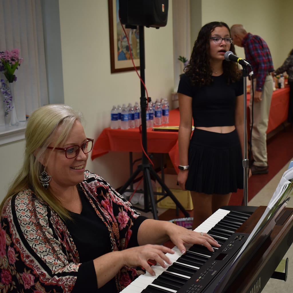 Christine Brown, one of or coordinators, plays piano and accompanies a student who is singing
