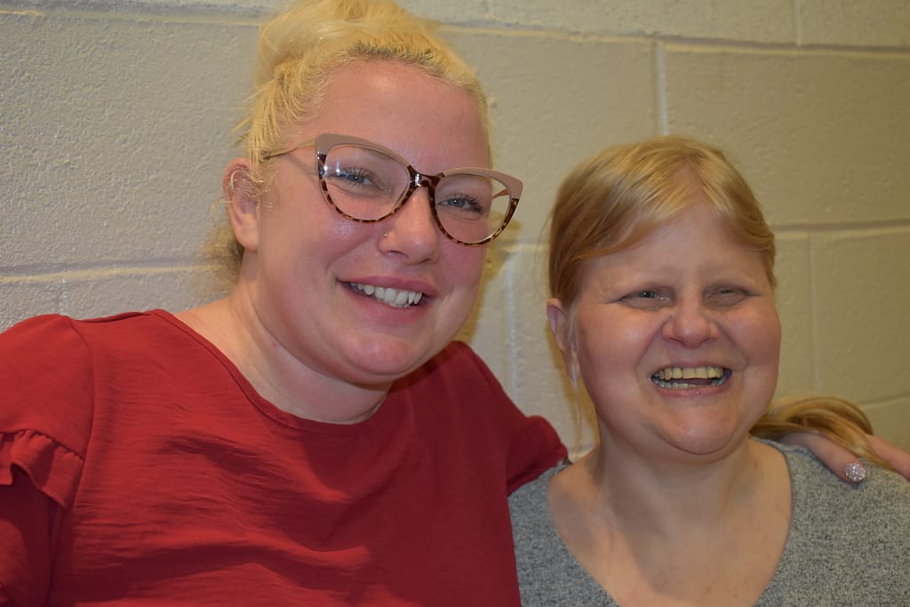 A female advocate puts her arm around her female partner at our annual Spaghetti Dinner