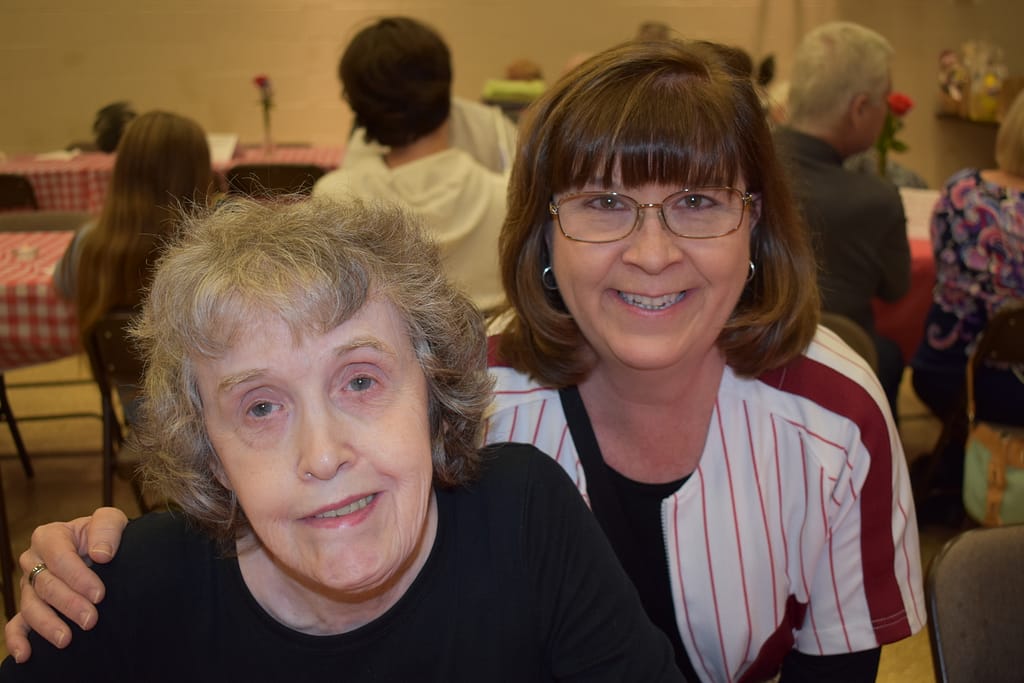 A female advocate put her arm around her female partner at our annual Spaghetti Dinner
