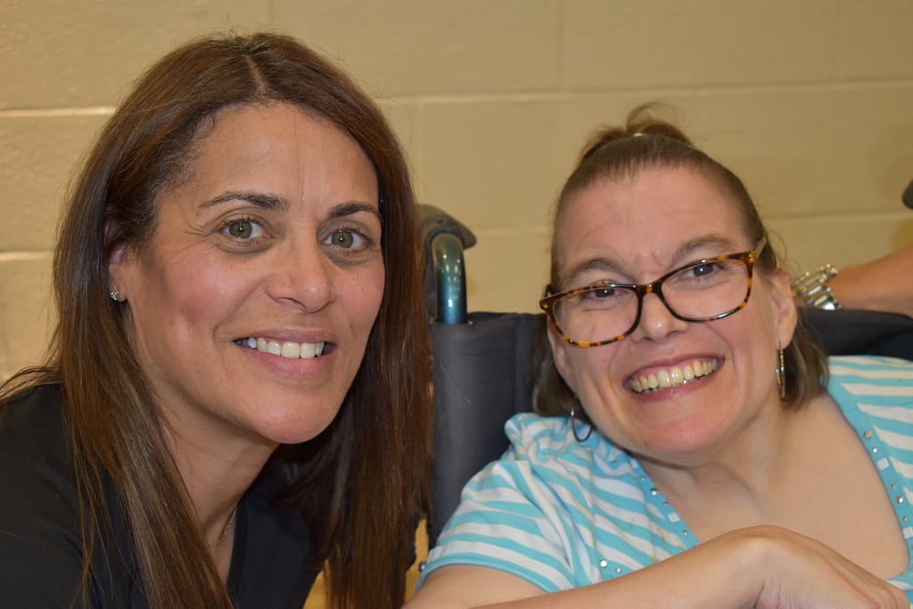 A female advocate and her female partner flash big smiles at our annual Spaghetti Dinner